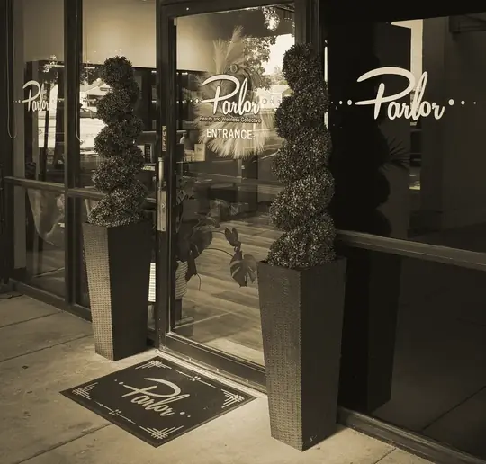 Parlor&rsquo;s door at Suite 215: the Parlor script on frosted glass, two topiaries and a Parlor doormat
